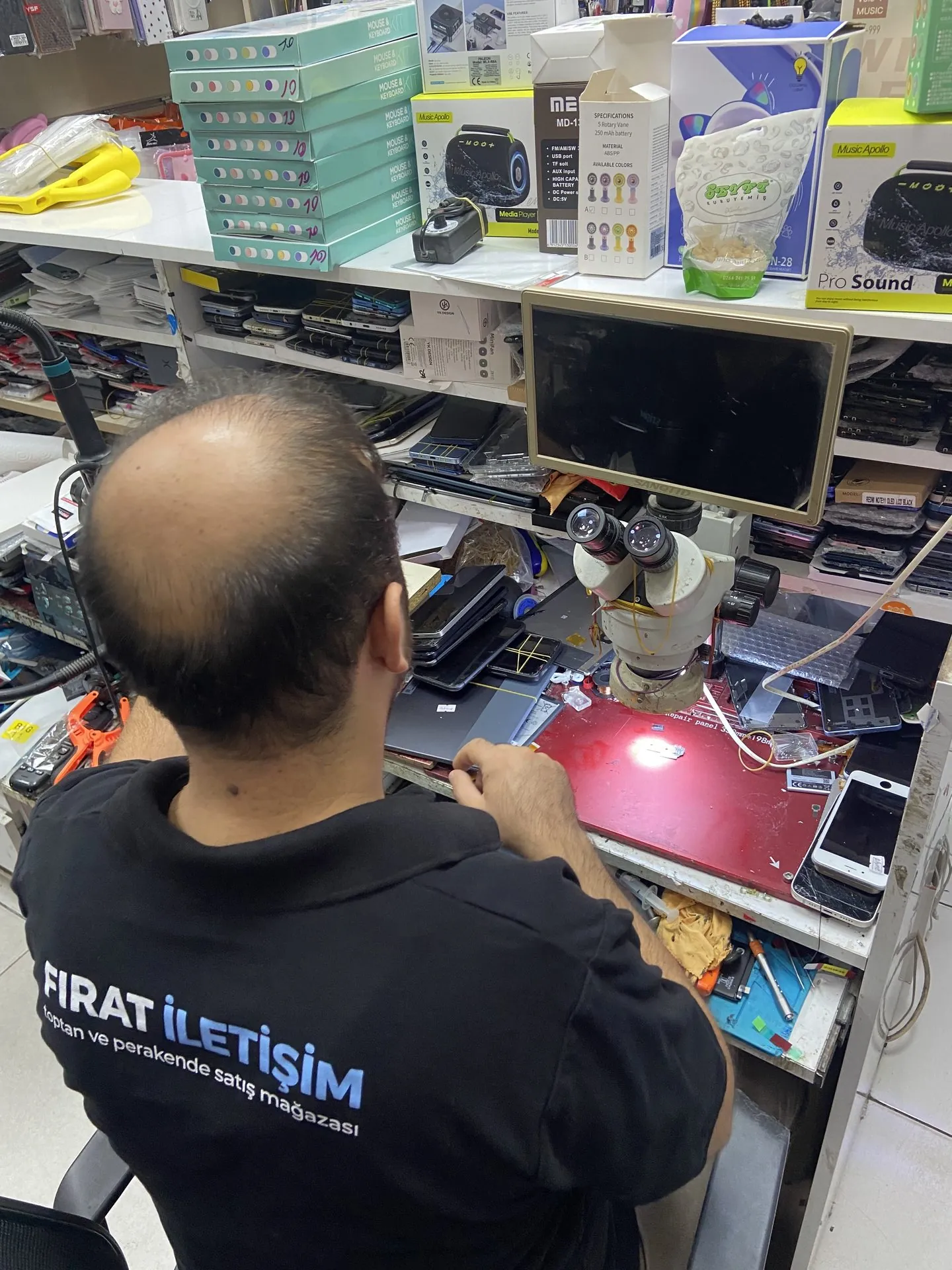 Fırat İletişim teknisyeninin telefon ve tablet tamir tezgâhında çalışması